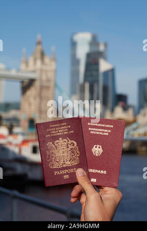 Mano che tiene il passaporto britannico insieme con altri passaporto UE contro il simbolo di Londra. Il viaggio dopo Brexit. Foto Stock