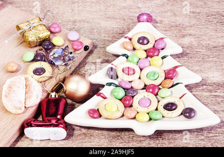 Piastra in forma di albero di Natale con salatini e dolci. Funny vetro giocattolo di ratto. Foto Stock