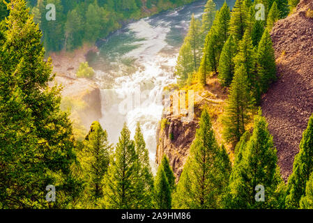 La luminosa luce del sole su misty cascata nella foresta verde e scogliere. Scenic primavera vista della caduta dell'acqua. Foto Stock