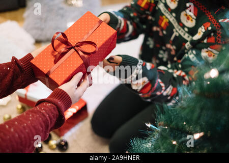 Childs mani dando rosso presente a womans mani Foto Stock