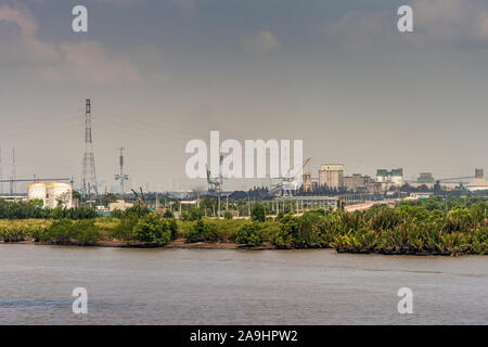 Lungo il fiume Tau, Vietnam - Marzo 12, 2019: Phuoc Khanh area. Cluster di impianti industriali con serbatoi, sili, gru, camini sotto luce blu cloudsca Foto Stock