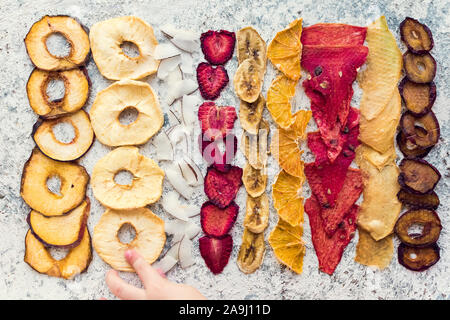 Mano del bambino di raggiungere sani di frutta fatta in casa da trucioli di mela, arancio, banana, fragola. Organica Vegana la dieta alimentare. Frutta secca. P vegetariano Foto Stock