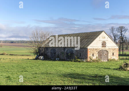 Abbandonato un fienile in pietra sorge in un verde prato. Industrial dairy farm. Podlasie, Polonia. Foto Stock