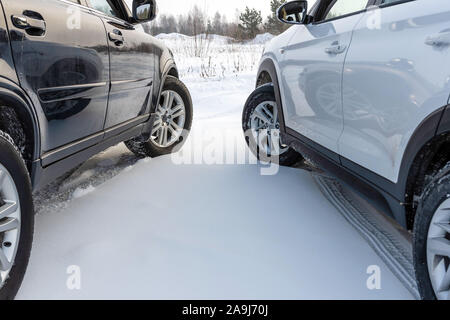 Il bianco e il nero di un suv auto parcheggiate in un campo nevoso. Foto Stock