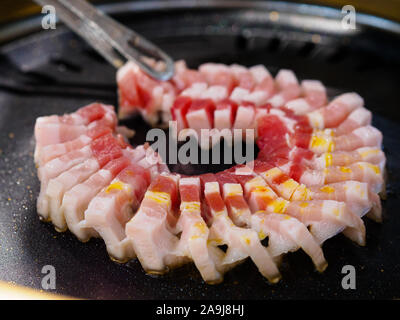 Close up di pancetta di maiale essendo alla griglia su un tradizionale coreano / Chinese / stile asiatico grill Foto Stock