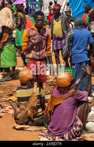 Eth124 Etiopia, Sud Omo, Key Afer, mercato del giovedì, uomo che parla alle donne di commercianti indossando cappelli calabash Foto Stock