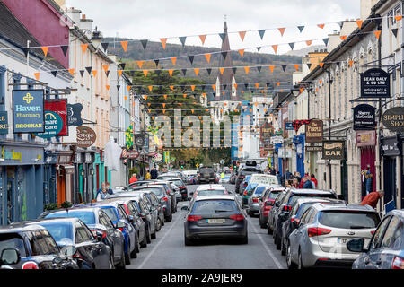 Pub, negozi, alberghi e ristoranti su un halloween decorate street in Kenmare, nella contea di Kerry, Irlanda. La Croce santa chiesa cattolica nella distanza. Foto Stock