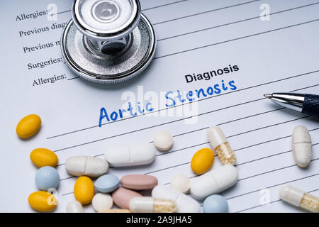 Stenosi aortica diagnosi scritto su un modulo con uno stetoscopio, penna e pillole Foto Stock