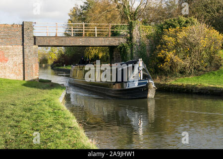 In autunno la scena; narrowboat passando sotto il ponte 28 sul Grand Union Canal, Weedon, Northamptonshire, Regno Unito Foto Stock