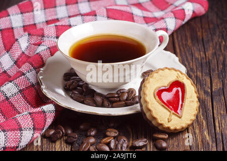 Tazza di caffè con i cookie sul tavolo rustico dissimulata tovaglia rosso Foto Stock