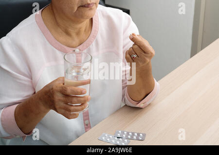 Mal di testa donne anziane tenere in mano la medicina con un bicchiere di acqua, sensazione di stress, emicrania, problema di salute concetto Foto Stock