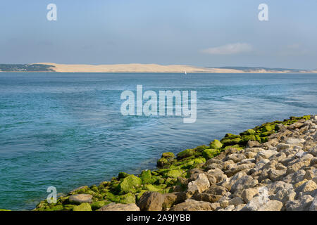 Litorale con una costa di protezione in pietra a Cap-ferret con la duna del Pilat in background. Comune della Gironde dipartimento in Francia Foto Stock