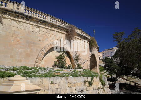 Parete storiche del centro fortificato di Valett, la città capitale di Malta, contro il cielo blu, accanto al parco, giardino con alberi verdi, senza persone Foto Stock