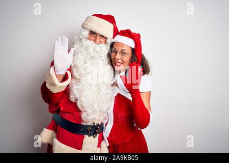 La mezza età giovane indossando il costume di Santa avvolgente isolato su sfondo bianco rinuncia a dire ciao felice e sorridente, gentile gesto di benvenuto Foto Stock