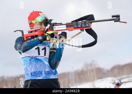 Sportive biatleta Yegorova Polina Kazakistan la carabina in posizione eretta. Biatleta nel poligono di tiro della gioventù competizioni di Biathlon Coppa Est Foto Stock