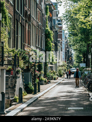 Amsterdam, Paesi Bassi - 21 Luglio 2019: gli abitanti del posto a piedi sul canal street in pigro pomeriggio Foto Stock