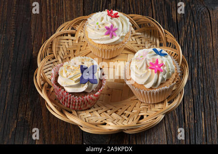 Tre i tortini con la crema nella piastra di vimini scuri su un tavolo di legno Foto Stock
