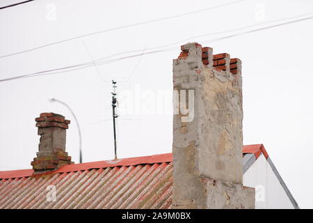 Due vecchi camini distrutti su un tetto rurale Foto Stock