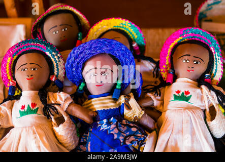 Fila di bambole di indossare abiti tradizionali e colorati di cappelli di paglia, Madagascar Foto Stock