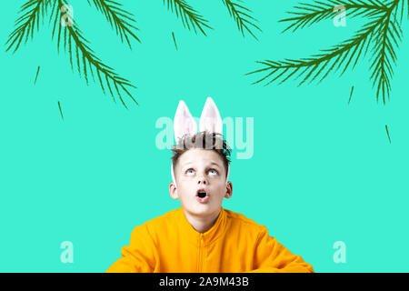 Ragazzo sorpreso in una giacca gialla e le orecchie di lepre su un sfondo di menta Foto Stock