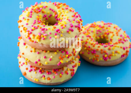 Le ciambelle con spruzza su sfondo blu. Pila di ciambelle colorate. Foto Stock