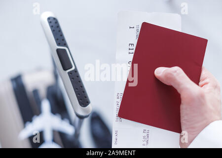 Viaggio di affari. Un uomo con un passaporto e biglietto e il bagaglio, close-up i dettagli. Foto Stock