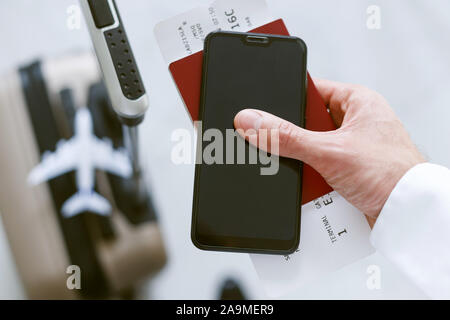 La registrazione elettronica tramite smartphone al bordo del piano. Un uomo con una valigia possiede un telefono cellulare biglietto di viaggio e passaporto. Foto Stock