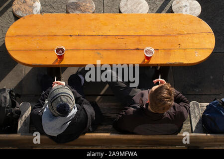 Due amici godono di una pinta di birra e una sigaretta a un tavolo al di fuori Foto Stock