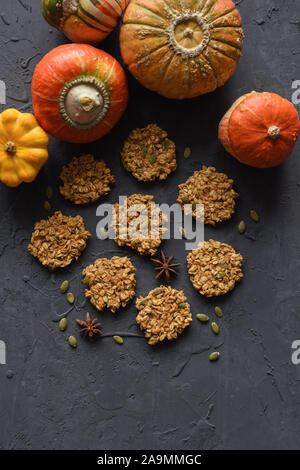 Vegan senza glutine il concetto di cottura. Flatlay di prima colazione fatta in casa biscotti di farina di avena e zucche invernali su sfondo nero spazio copia Foto Stock