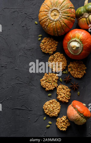 Vegan home concetto di cottura. Flatlay di zucca farina di avena i biscotti con semi e zucche invernali su sfondo nero spazio copia Foto Stock