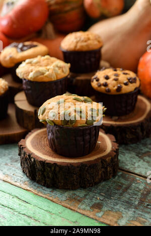 Una sana dolci fatti in casa del concetto. Imperfetta muffin di zucca con semi e cioccolato su lastre di legno sul malandato verde sullo sfondo di legno vista laterale copia spa Foto Stock