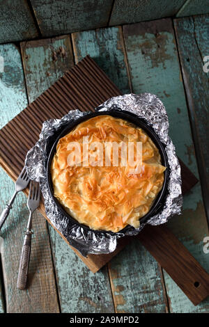 In stile greco con pasticceria di pasta fillo. In casa la torta in fogli di carta per cottura su squallido sfondo blu spazio copia Foto Stock