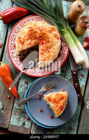 Piatto di laici torta fatta in casa con verdure crude e i semi di melograno blu su sfondo di legno. In stile greco con pasticceria di pasta fillo vista aerea Foto Stock