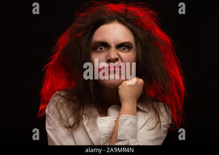 Divertimento pazzo giovane donna con capelli soffici su sfondo nero fare timido grimace Foto Stock