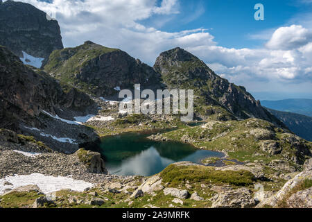 Vista sul lago Elenino sotto la cima di Malyovitsa in una giornata estiva soleggiata. Lago nel parco nazionale di Rila, la catena montuosa di Malyovitsa, Bulgaria. Foto Stock