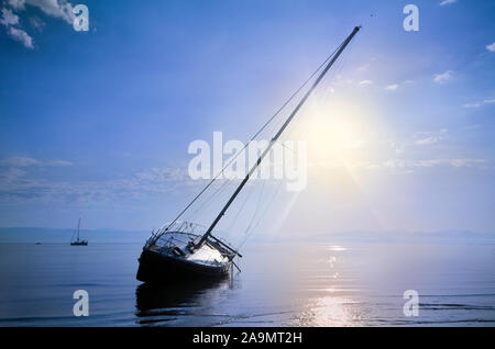 Blu, misty dawn su una spiaggia di Corfù con una barca a vela Foto Stock