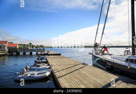 Gli uomini di vela di manovre in porto con barche e il dock in estate, Castine, Maine, New England, STATI UNITI D'AMERICA Foto Stock