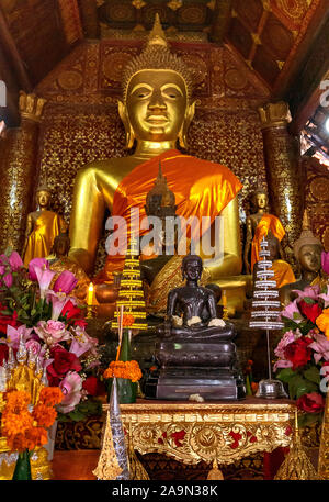 Statue di Buddha e offerte floreali in un Tempio o un Wat nella pittoresca città di Luang Prabang, patrimonio dell'umanità dell'UNESCO, in Laos. Sud-est asiatico. Foto Stock