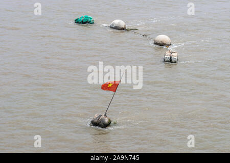 Lungo il fiume Tau, Vietnam - Marzo 12, 2019: boe di ripiego su acqua marrone, con un cittadino vietnamita falg della stella gialla sul rosso. Foto Stock