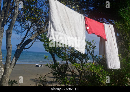Asciugamani e una t-shirt rossa sono appesi su una linea per asciugare in corrispondenza di un lato mare campeggio Foto Stock