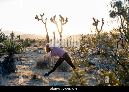 Giovane donna felice giocando lo yoga ed esprimendo fitness generale nei ritratti. Deserto Mojave Joshua Tree, CA USA Foto Stock