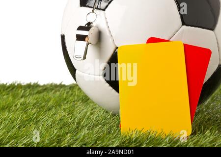 Solo bianco e nero sport soccer ball con arbitro fischia e il giallo e il rosso arbitro carte con il fuoco selettivo su erba verde su bianco backgro Foto Stock