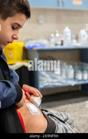 Giovane ragazzo adolescente in ospedale. Bambino con taglio avvolto nel gabinetto medico in ospedale. Kid mostra ventre ferita. Concetto per ferita dalla chirurgia. Foto Stock