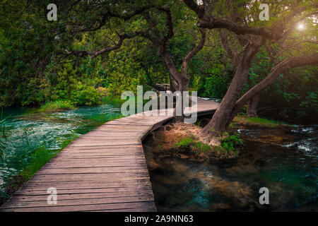 Ammirevole turistica ponte di legno nel fresco verde deep forest. Passeggiata in legno con clean brook e belle cascate, Parco Nazionale di Krka, Sibe Foto Stock