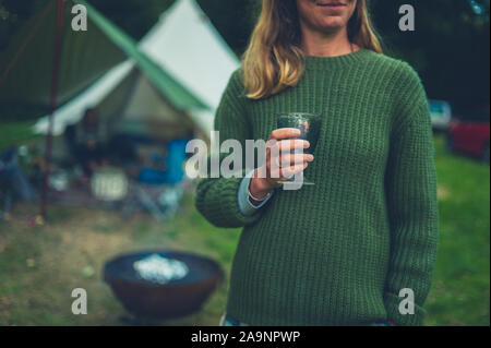 Una giovane donna è un bicchiere di vino al tramonto in un campeggio Foto Stock