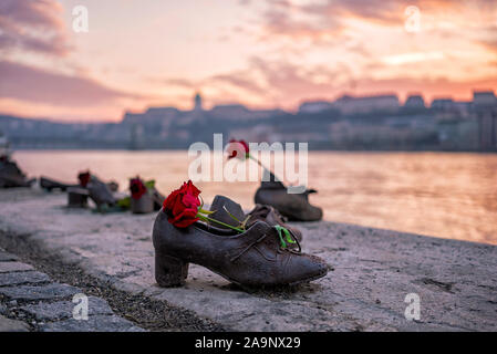"Le Zappe sulla sponda del Danubio' monumento in memoria delle vittime della Shoah durante la seconda guerra mondiale sulla riva del Danubio al tramonto a Budapest, Ungheria Foto Stock