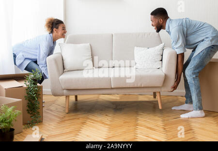 Allegro Afro coniugi posizionando il lettino Arredo camera vuota nella nuova casa Foto Stock