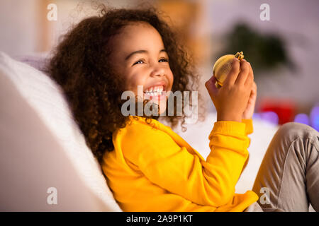 Carino african bambina giocando con il Natale Sfera decorativa Foto Stock