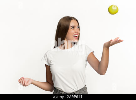 Ragazza Apple gettando in aria in piedi su sfondo bianco Foto Stock