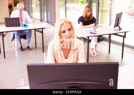 Alta angolazione di fiduciosa imprenditrice lavorando sul computer in ufficio. Foto Stock